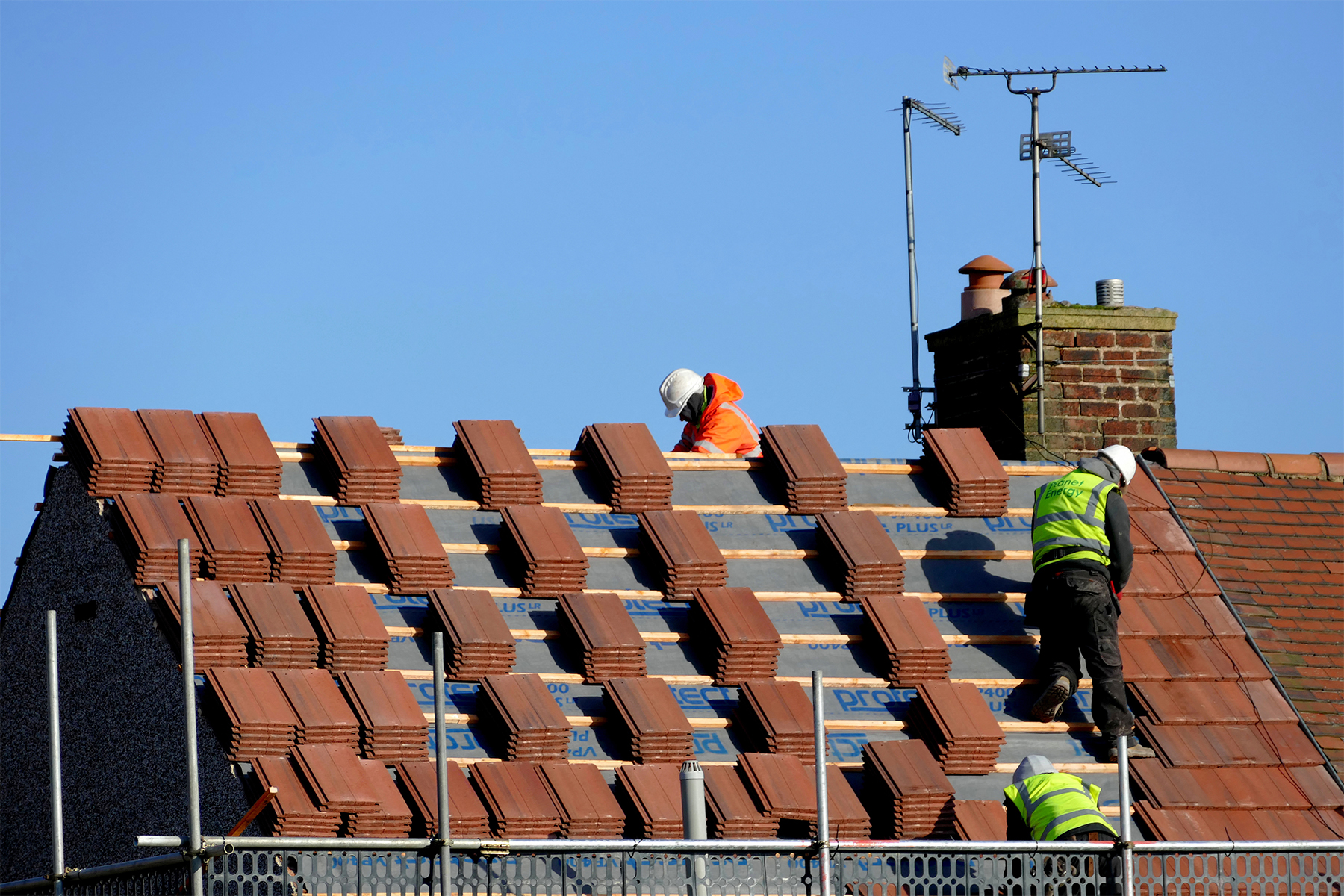 Sutton-in-Ashfield, Nottinghamshire, UK. February 19, 2016.  A group of workmen covering a roof of a semi-detached house with tile slates, taking care to stand on the lats as they dice with danger.